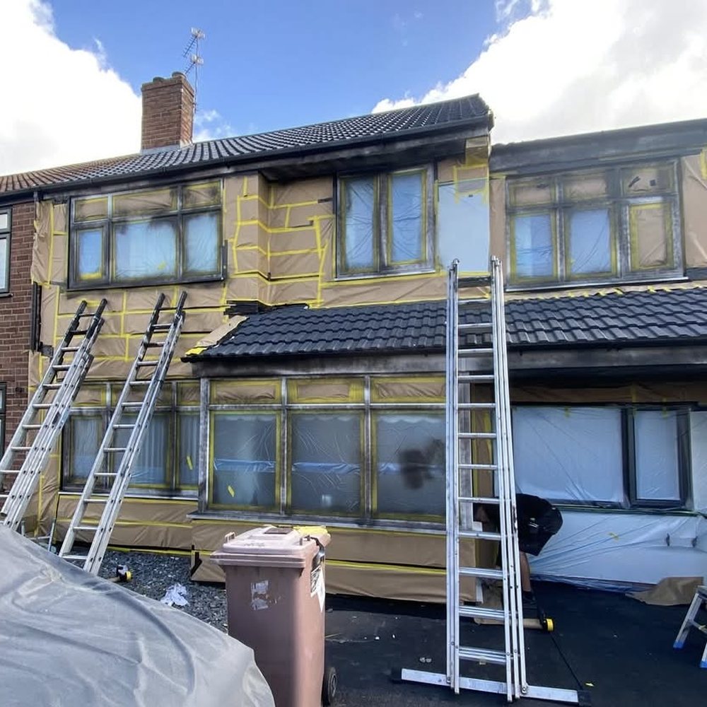 The same semi-detached house mid-job, masked up with ladders in place before spraying